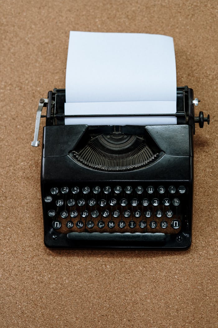 Classic black typewriter with Cyrillic keys on a cork board for a retro aesthetic.